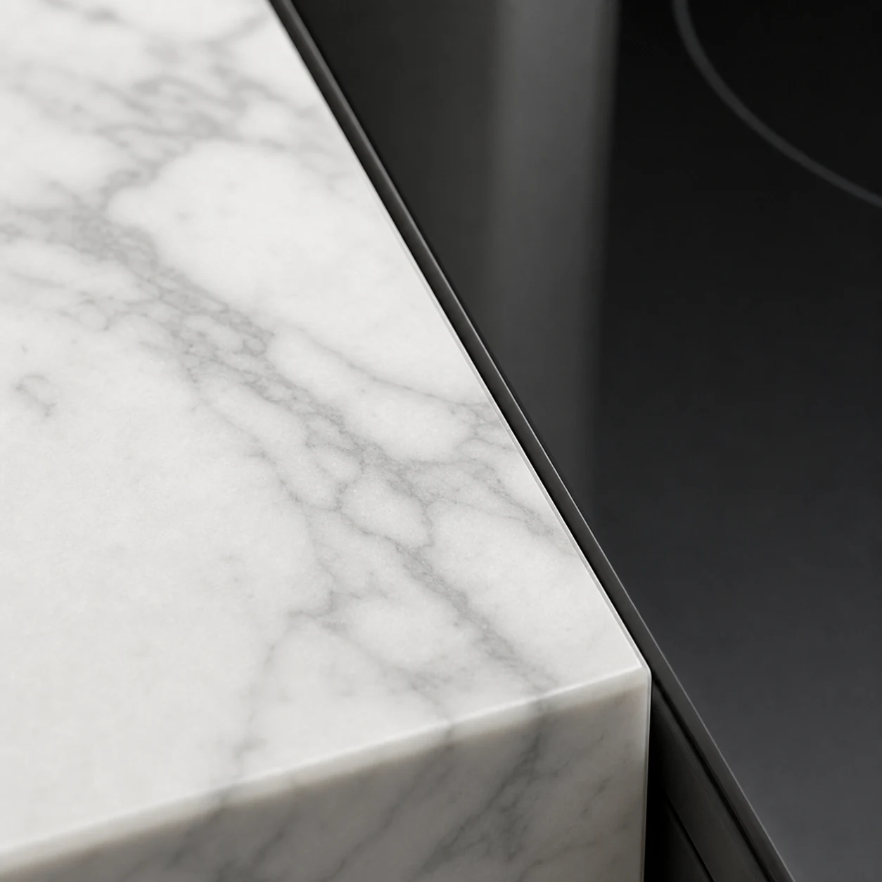 White marble countertop edge beside a black induction cooktop